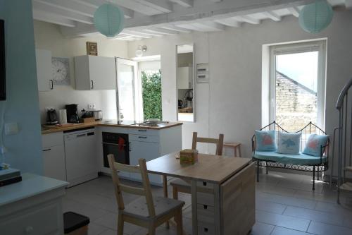 a kitchen with white cabinets and a table and chairs at 50 m2 de charme au coeur des plaisirs de la côte in Luc-sur-Mer