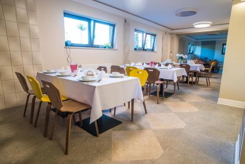 a dining room with white tables and yellow chairs at Dom Wypoczynkowy Simurg in Mikoszewo