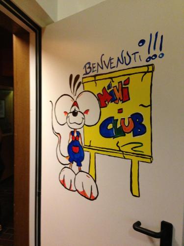 a cartoon mouse holding a sign on a bathroom door at Family & Wellness Hotel Fontana in Vigo di Fassa