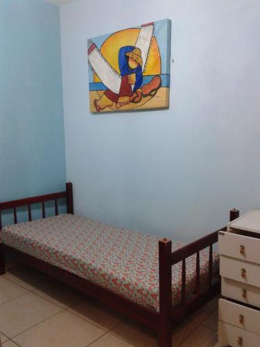 a bed in a room with a painting on the wall at casa Barra Velha - SC in Barra Velha