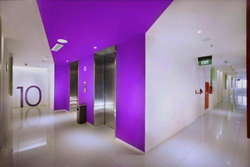 a hallway with purple walls and a elevator at Zuri Express Lippo Cikarang in Cikarang