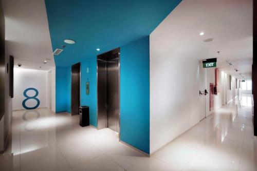 a hallway with blue walls and a number eight sign at Zuri Express Lippo Cikarang in Cikarang