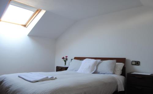 a bedroom with a bed with white sheets and a window at Casa La Torre in Isla de Arosa