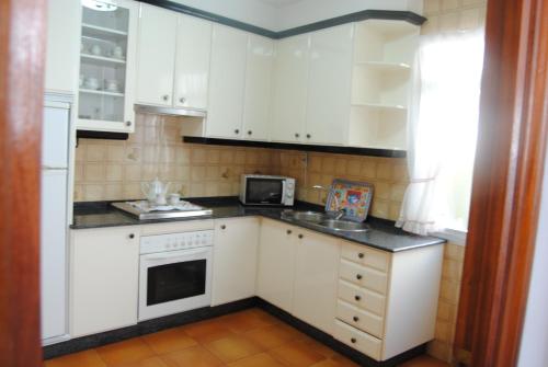 a small kitchen with white cabinets and a microwave at Casa La Torre in Isla de Arosa