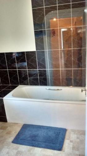 a bathroom with a bath tub and a blue rug at Derwent Street Apartment 1 - 3 Bed Self Catering Apartment - Self Contained - 1 Double & 2 Single Rooms in Workington
