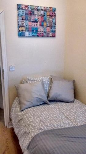a bed with two pillows and a painting on the wall at Derwent Street Apartment 1 - 3 Bed Self Catering Apartment - Self Contained - 1 Double & 2 Single Rooms in Workington