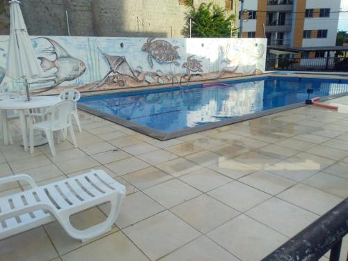 einen Pool mit einem Tisch, einem Tisch und Stühlen in der Unterkunft Condominio Port. da cidade Aracaju in Aracaju