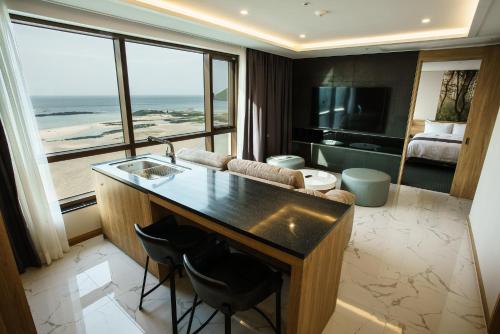 a room with a kitchen with a view of a living room at Utop Ubless Hotel Jeju in Jeju