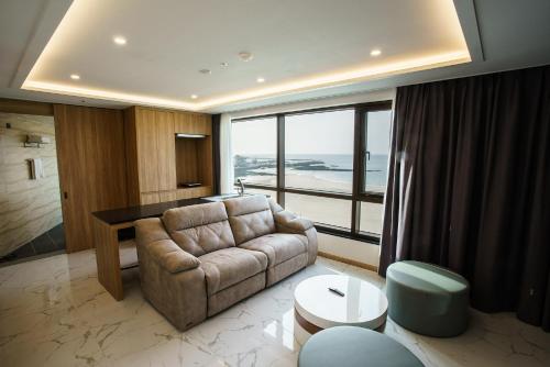 a living room with a couch and a large window at Utop Ubless Hotel Jeju in Jeju