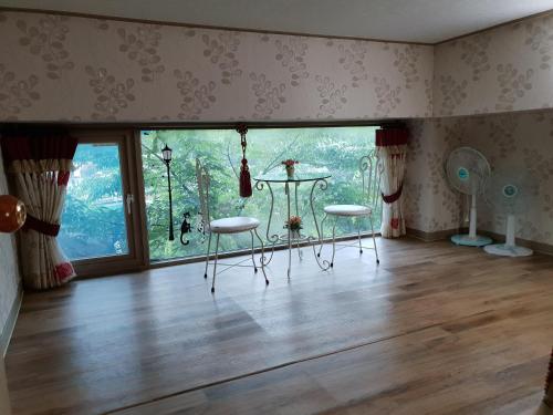 a room with two chairs and a large window at Jirisan One Night Two Days Pension in Gurye
