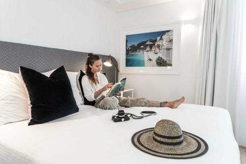a woman sitting on a bed with a hat on it at Tingirana Noosa in Noosa Heads