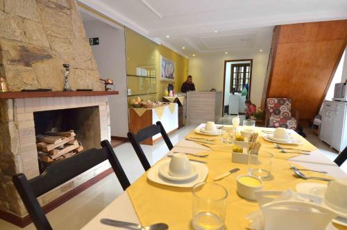 a dining room with a table and a fireplace at Pousada Campos Montreal in Campos do Jordão