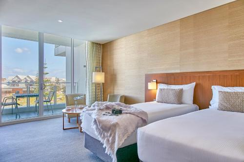 a hotel room with two beds and a balcony at The Sebel Mandurah in Mandurah