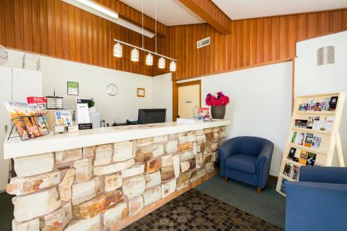 a waiting room with a stone counter and a blue chair at Cudgegong Valley Motel in Mudgee