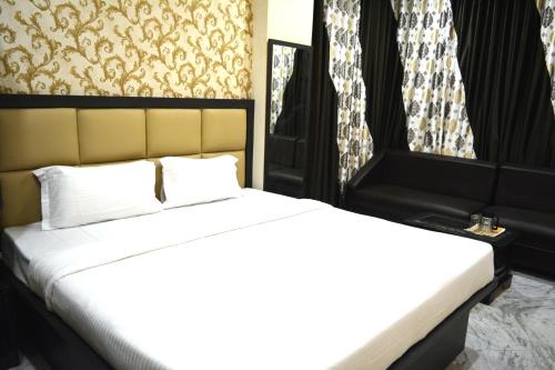 a bedroom with a bed with white sheets and curtains at Olive suites in Patna
