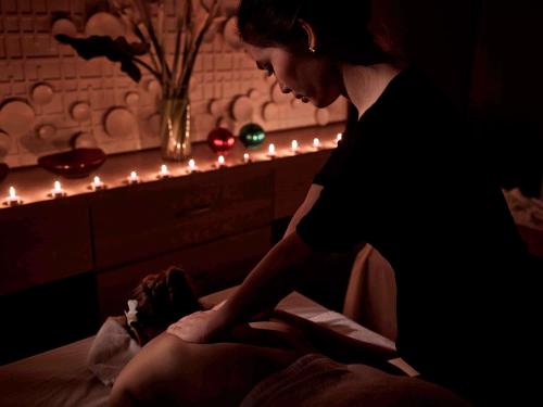 a woman sitting on a bed with a doll at Pullman Hanoi in Hanoi