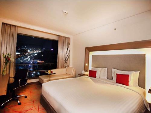 a hotel room with a large bed and a window at Novotel Ahmedabad in Ahmedabad