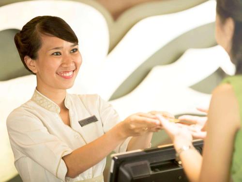 a woman is sitting at a cash register at Novotel Bali Nusa Dua in Nusa Dua