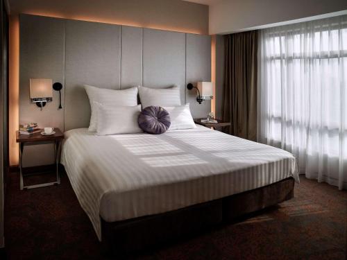a bedroom with a large bed with white pillows at Pullman Hanoi in Hanoi
