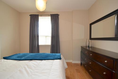 a bedroom with a bed and a dresser and a window at The SoMa Furnished Residences in Hamilton