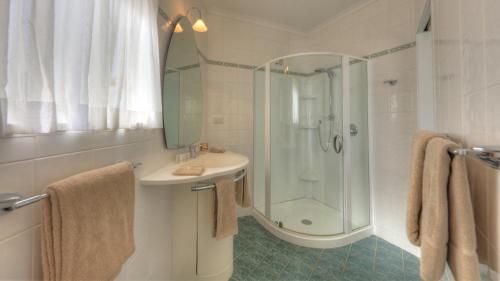 a white bathroom with a shower and a sink at Ocean Breeze Cottages in Burnt Pine