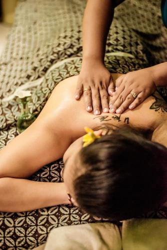 a woman laying on a bed with her hands on her back at Famous Hotel Kuta Formerly Permata Kuta Hotel in Kuta