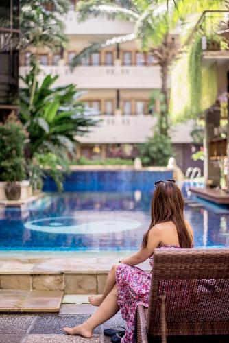 a young girl sitting in a chair next to a swimming pool at Famous Hotel Kuta Formerly Permata Kuta Hotel in Kuta