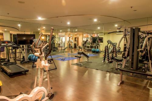 a gym with a lot of exercise equipment and a mirror at Famous Hotel Kuta Formerly Permata Kuta Hotel in Kuta