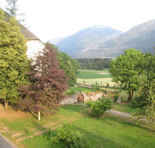 a view of a field with a bridge and mountains at Schloss Manndorf Gästehaus in Kötschach
