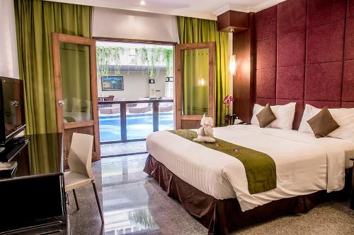 un dormitorio con una cama con un osito de peluche sentado en ella en Famous Hotel Kuta Formerly Permata Kuta Hotel, en Kuta