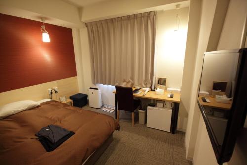 高松市にある高松センチュリーホテルのベッドとデスクが備わるホテルルームです。