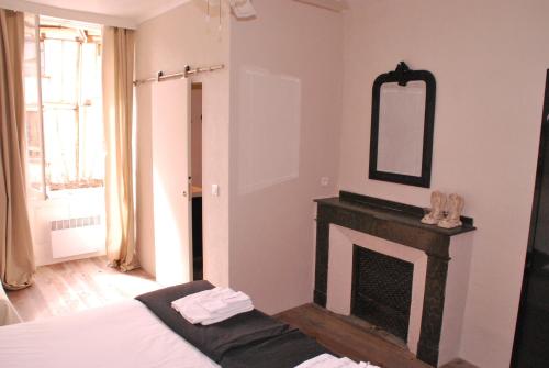 a bedroom with a fireplace and a mirror on the wall at La Maison au Puits in Cordes-sur-Ciel