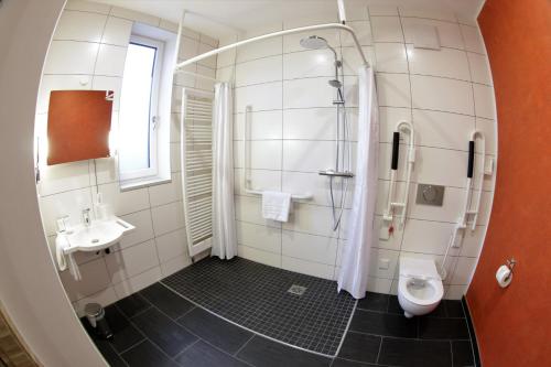 a bathroom with a shower and a toilet and a sink at Hotel WITT am See in Weiherhammer