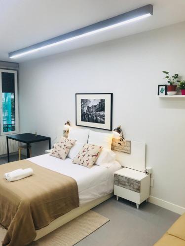 a white bedroom with a large bed and a table at Apartamento Kasa Tomas Gros in San Sebastián