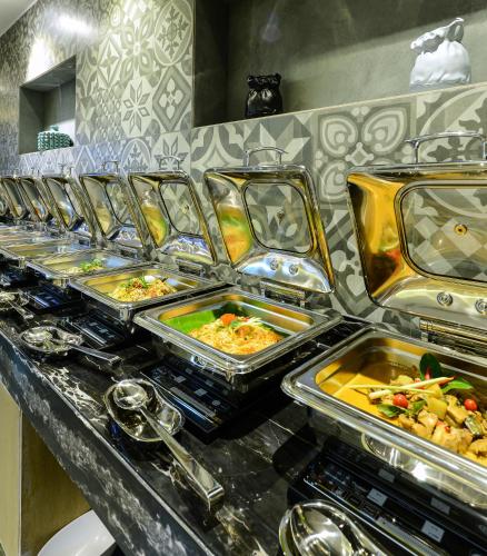 a buffet line with trays of food on a counter at Howard Johnson by Wyndham, Kolkata Airport in Kolkata