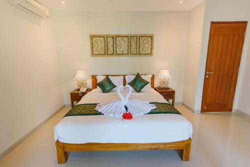 a bedroom with a bed with white sheets and two lamps at Taman Amartha Villa Ubud in Ubud