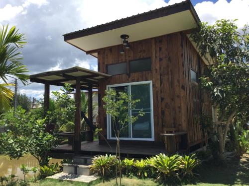 a tiny house with a porch and a large window at Baan Suan La Moon in Chiang Khan