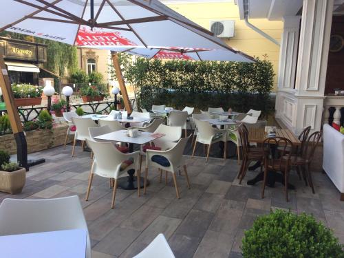 um restaurante com mesas e cadeiras e um guarda-sol em Hotel Castel em Râmnicu Vâlcea