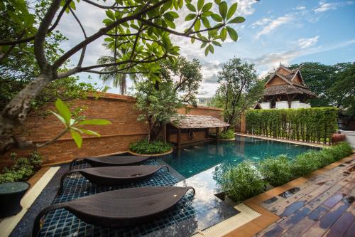 a courtyard with a swimming pool with chairs and a table at Shinnabhura Historic Boutique Hotel in Phitsanulok