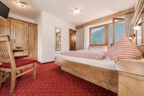a bedroom with a bed and a chair and a window at Haus Christine in Ried im Zillertal