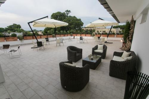 a patio with chairs and tables and umbrellas at Love & Fama Hotel in Sabaudia