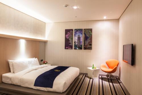 a bedroom with a bed and a orange chair at Taipei 101 SPARKLE Hotel in Taipei