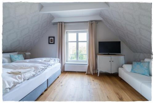 a bedroom with a bed and a couch and a television at Ferienhaus Malve in Liepe in Rankwitz