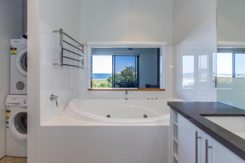 ein weißes Bad mit einer Badewanne und einem Fenster in der Unterkunft Aquatic Visions Studio Apartments in Margaret River Town