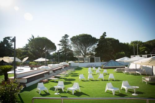 a row of white chairs on a grass field at Art Hotel Museo in Prato