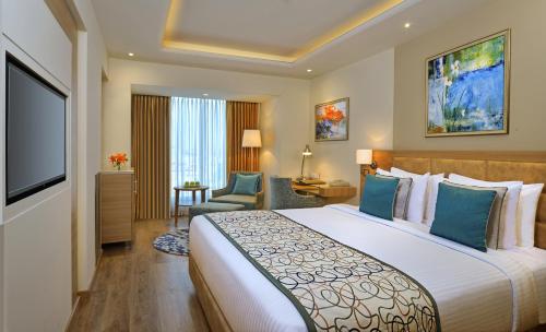 a hotel room with a large bed and a television at Golden Sarovar Portico in Amritsar