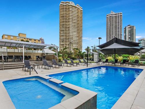 una piscina con sedie e ombrelloni in città di Sunbird Beach Resort Gold Coast a Gold Coast