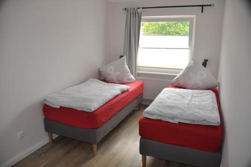two beds in a room with a window at Hotel & Ferienunterkünfte Hus Seeblick in Fehmarn