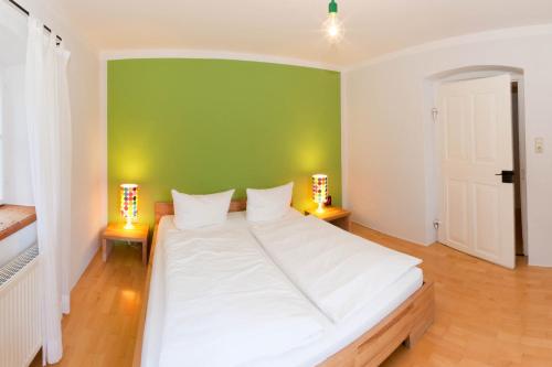 a large white bed in a room with a green wall at Zeitraumferien in Bernau am Chiemsee