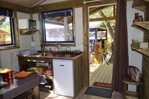 une cuisine avec un évier et une porte menant à une terrasse couverte dans l'établissement Camping Routes du Monde ATC La Hume-Arcachon, à Gujan-Mestras